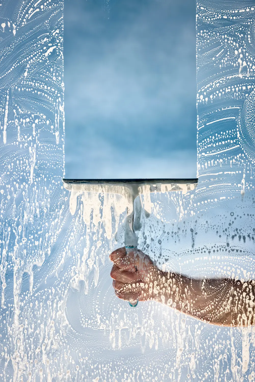 Fensterputzer wäscht ein Fenster mit einem Abzieher